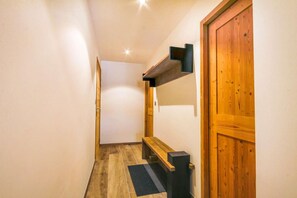 A narrow hallway with wooden flooring, a bench, a door, and a wall-mounted shelf. - 100m from ski slopes, 1st floor, balcony, parking, tv, 86m², Morzine (Morzine)