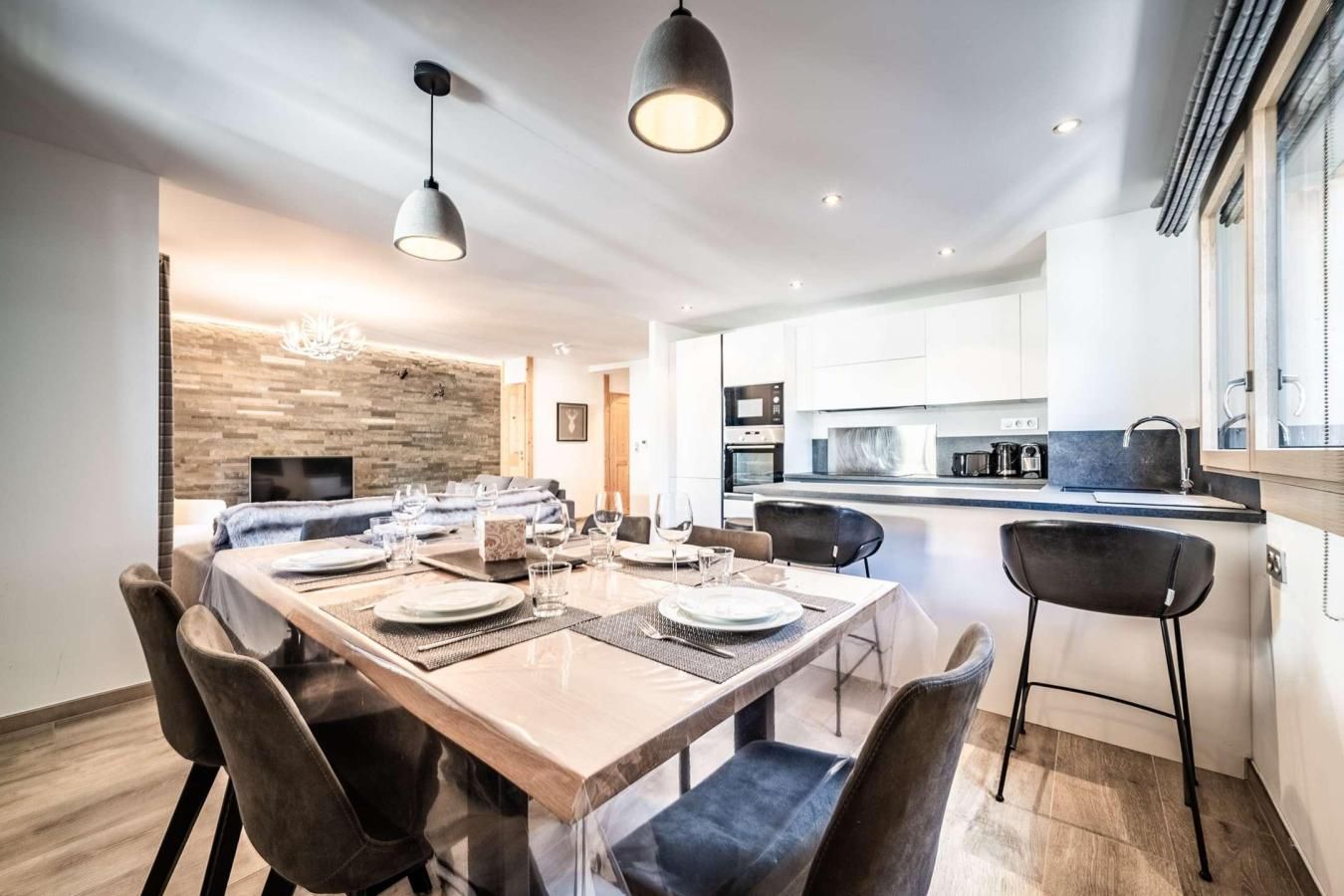 A modern kitchen with white cabinets, a central island, and a dining area with a wooden table and chairs.