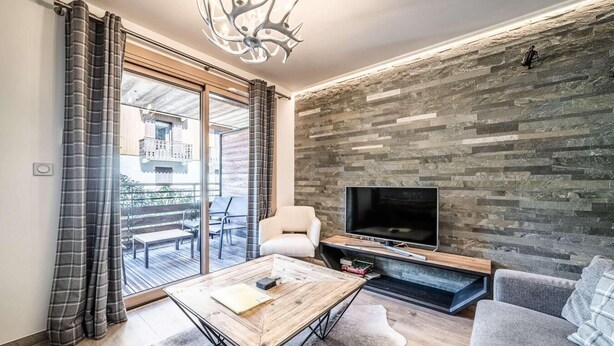 Een moderne woonkamer met een grote televisie, een open haard en een balkon met tuinmeubilair.