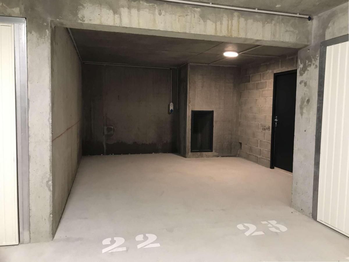 Un intérieur spacieux et brut, avec des murs en béton et un plancher plat, comprenant une porte et une petite fenêtre.