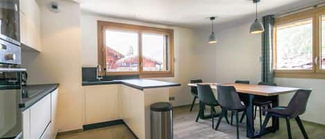 Una cocina moderna con comedor, suelo de madera y ventanas amplias.