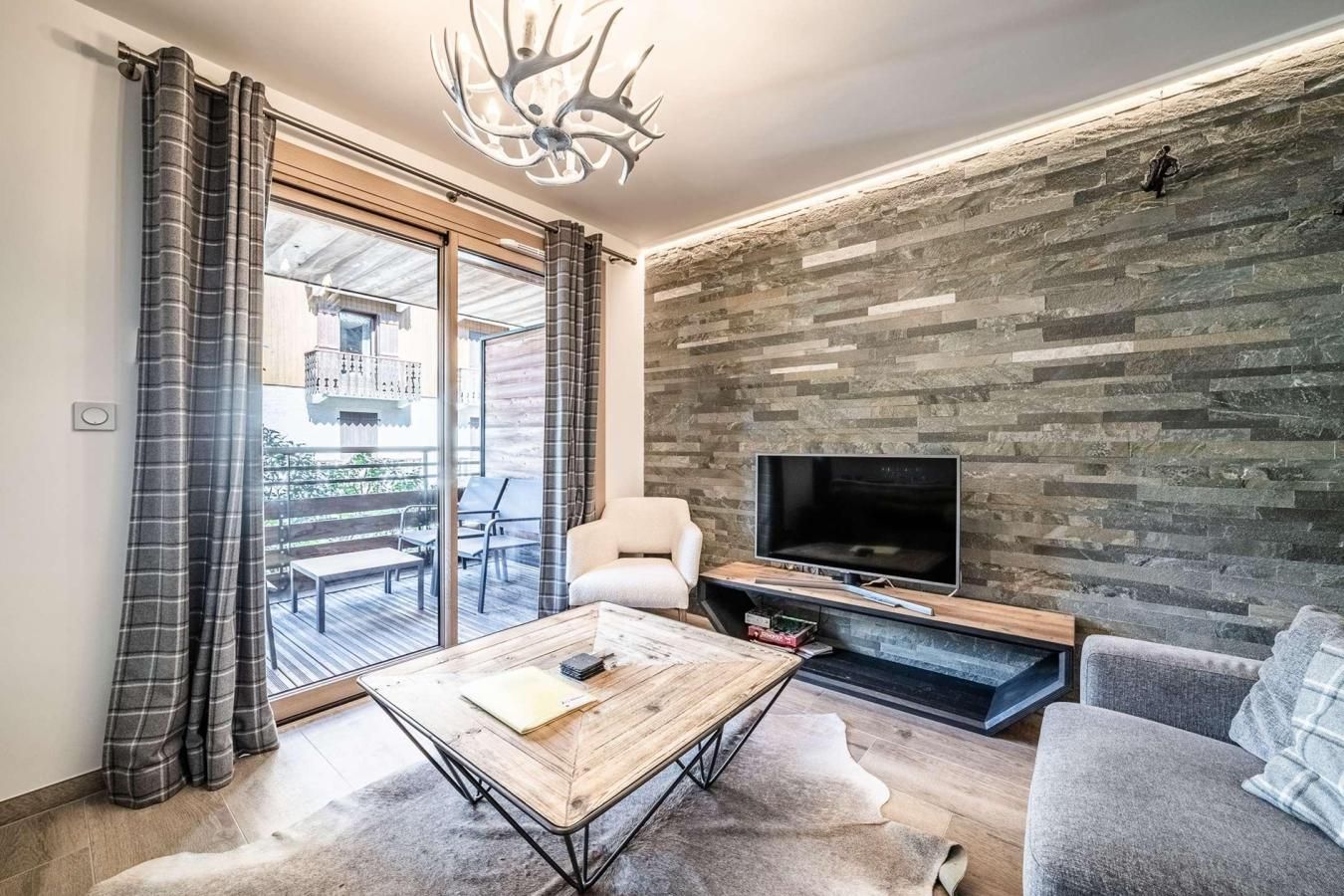 Un salon moderne doté d’un grand téléviseur, d’une cheminée et d’un balcon aménagé avec du mobilier d’extérieur.