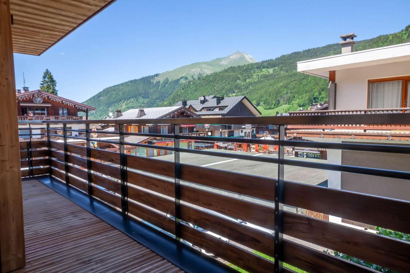 Un balcon en bois offrant une vue sur une montagne et des bâtiments.