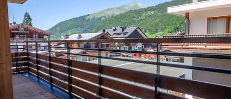Un balcon en bois offrant une vue sur une montagne et des bâtiments.