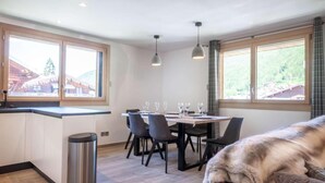 Een moderne keuken met een eethoek, grote ramen en een hond op een bank.
