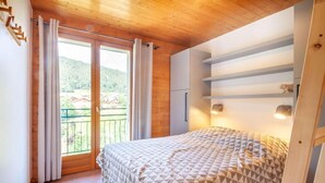 A bedroom with a bed, a sliding glass door to a balcony, and a wooden ceiling. - Ground floor, view mountain, balcony, parking, tv, 64m², Morzine (Morzine)