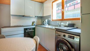 A compact kitchen with a washing machine, a sink, and a window overlooking a building. - Ground floor, view mountain, balcony, parking, tv, 64m², Morzine (Morzine)
