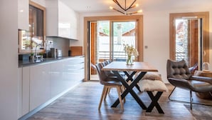 A modern kitchen with white cabinets, a wooden dining table, and black X-shaped legs.
