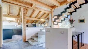 Une cuisine moderne dotée d’un four encastré, un coin repas avec une table en verre et un escalier menant à un niveau supérieur.