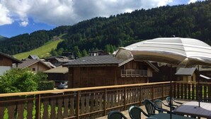 A terrace with outdoor seating, a wooden fence, and a view of a village and forested hills. - 1st floor, view mountain, terrace, parking, tv, 160m², Morzine (Morzine)