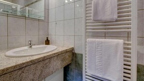 A bathroom with a granite countertop sink, a mirror, and a towel rack with two white towels. - 1st floor, view mountain, terrace, parking, tv, 160m², Morzine (Morzine)