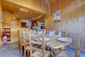 Puinen sisustus, jossa on neljän hengen ruokailutila. Tilaan kuuluu puupöydät ja -tuolit, keittiö sekä kyltti, jossa lukee ”MORZINE”.