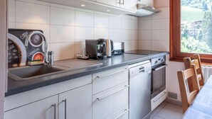 Una cocina moderna con cafetera, tostadora y vistas a un paisaje montañoso a través de una ventana.