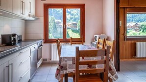 Una cocina con mesa, sillas y vistas a un paisaje montañoso a través de amplios ventanales.