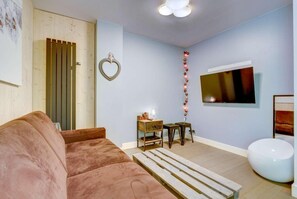 A living room with a sofa, a coffee table, a TV, and a decorative light string.