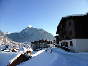 A snow-covered mountain town with buildings and a prominent mountain in the background.
