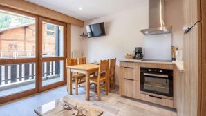 Een moderne keuken met houten kastjes, een inbouwoven en een flatscreen televisie aan de wand.