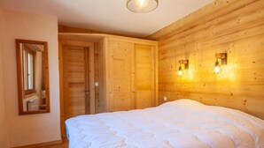 Een slaapkamer met een groot bed, houten wanden, een spiegel en twee wandlampen.