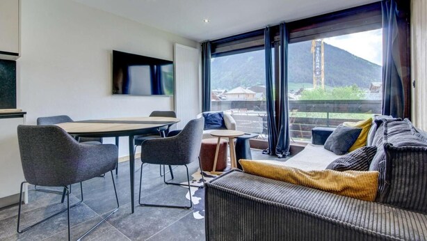 A modern hotel room with a dining area, a sofa, and a view of a mountain. - 200m from ski lifts, 2nd floor, balcony, parking, tv, ski locker, 47m², Morzine (Morzine)