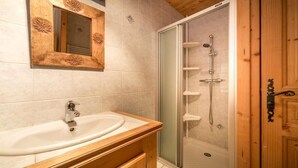 Ein Badezimmer mit Waschtisch aus Holz, einem Waschbecken, einem Spiegel und einer Duschkabine.