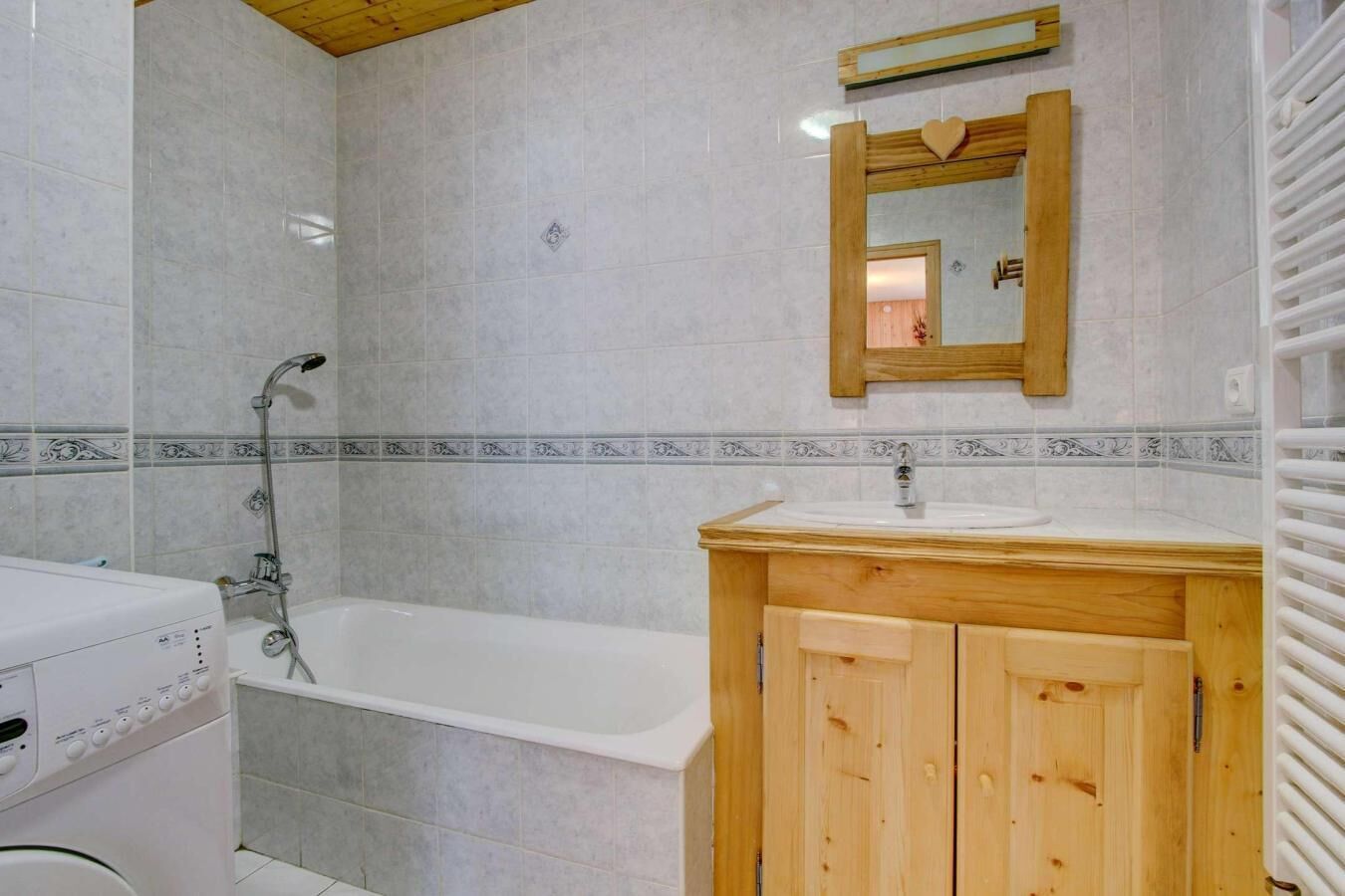 A bathroom with a wooden vanity, a white bathtub, and a shower area.
