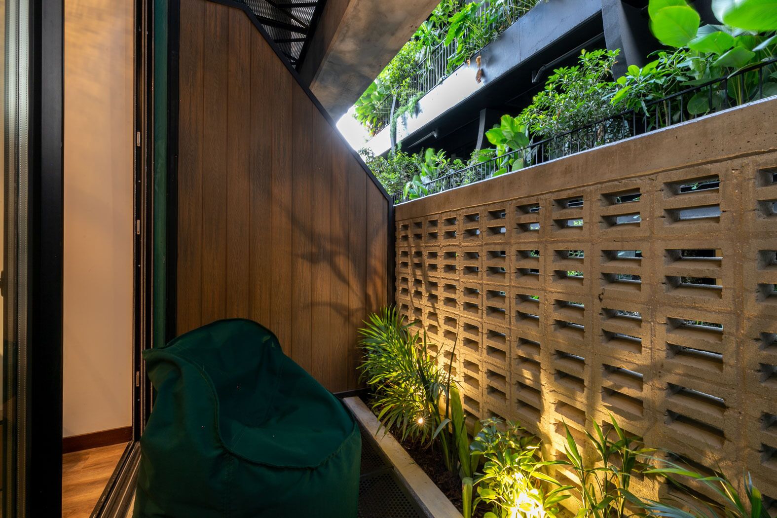 A modern interior with a wooden panel wall, a green chair, and a planter with plants.