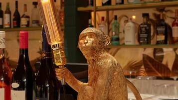 Una escultura de un mono dorado sosteniendo una botella, rodeada de diversas botellas de licor sobre estantes.