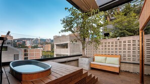 A rooftop terrace with a hot tub, wooden deck, and a bench.