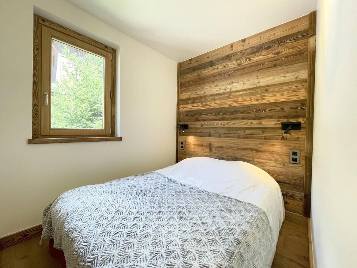 Un dormitorio con cama, ventana y cabecera de madera.