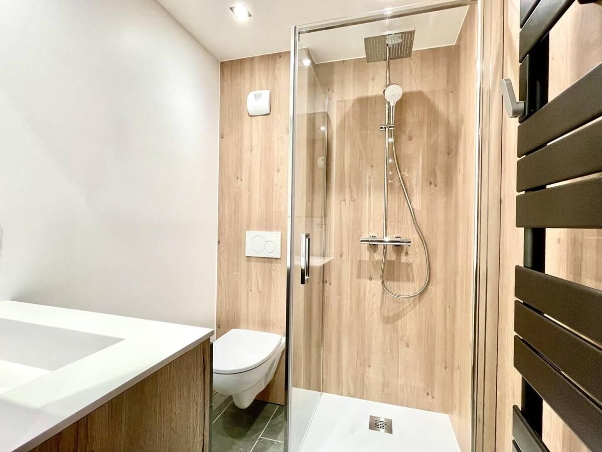 Une salle de bain moderne avec une douche à parois de verre, un lavabo blanc et des toilettes.