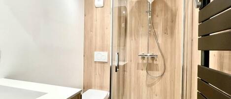 Une salle de bain moderne avec une douche à parois de verre, un lavabo blanc et des toilettes.
