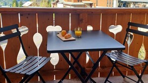 A balcony with a table and two chairs, overlooking a mountainous landscape with buildings in the background. - 50m from ski slopes, 2nd floor, swimming pool, sauna, hammam, balcony, tv, ski locker, 17m² (Champagny-en-Vanoise)