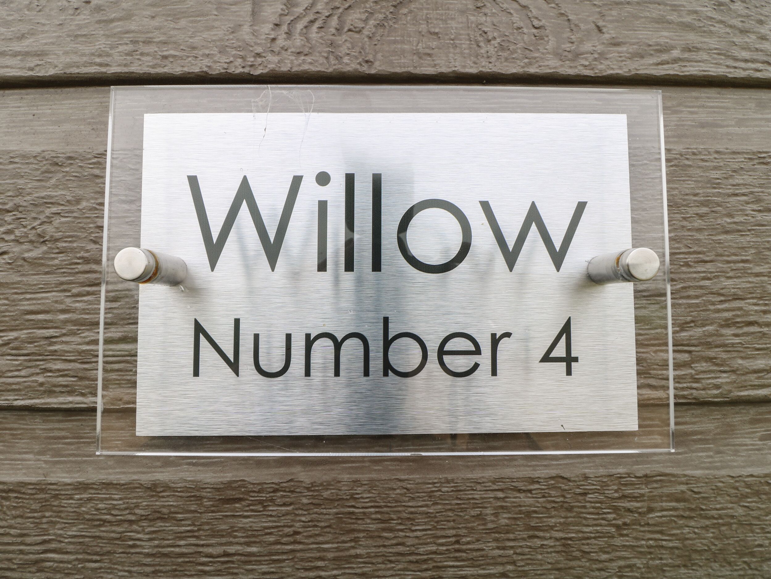 Una señal con el texto 'Willow Number 4' fijada a una pared con textura.