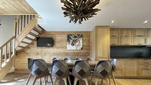 Una cocina moderna con armarios de madera, una mesa de comedor con sillas y una escalera.