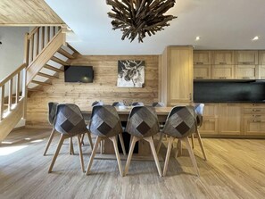 Una cocina moderna con armarios de madera, una mesa de comedor con sillas y una escalera.