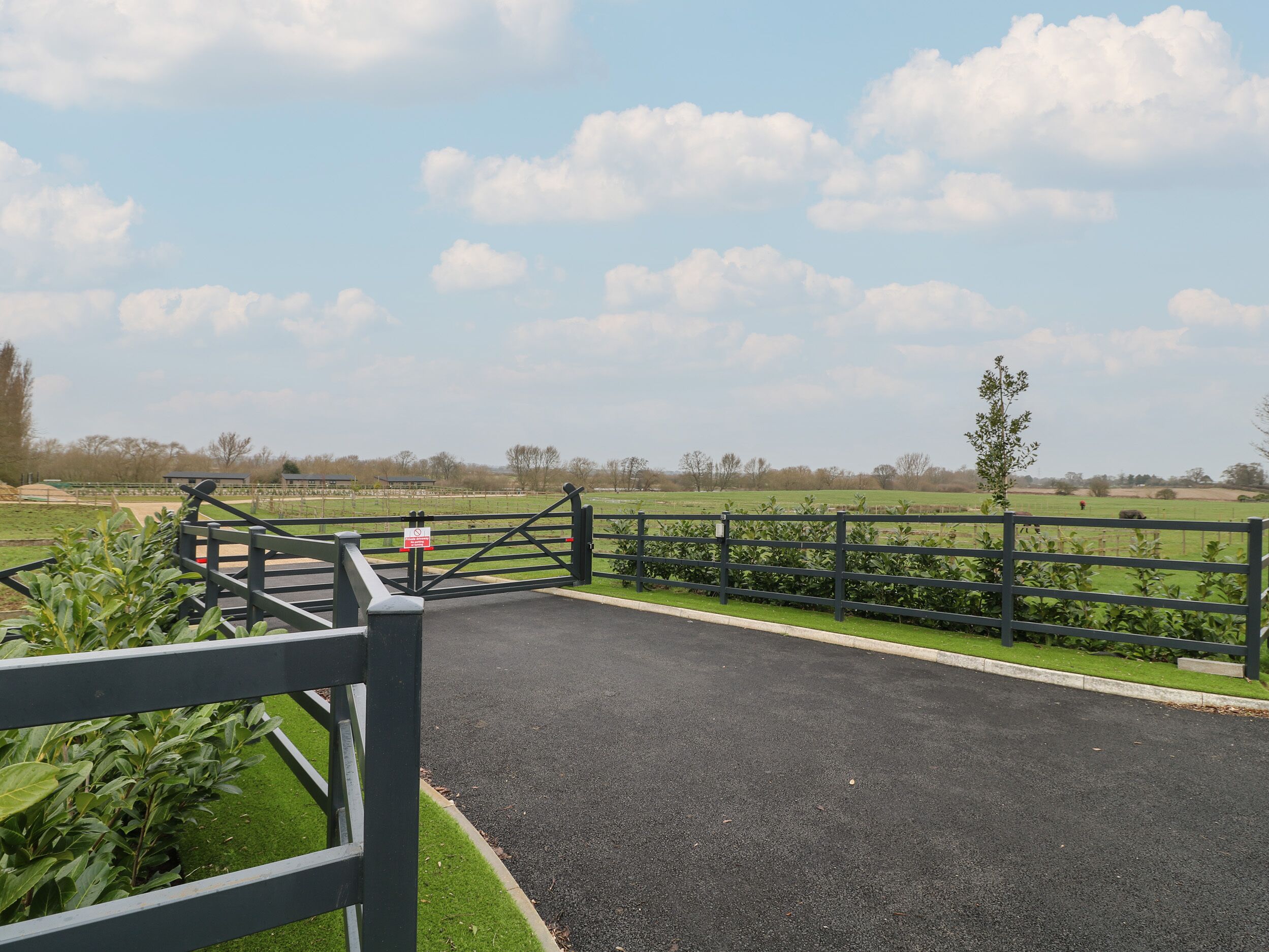A gated entrance to a park with a paved path leading to a grassy field.