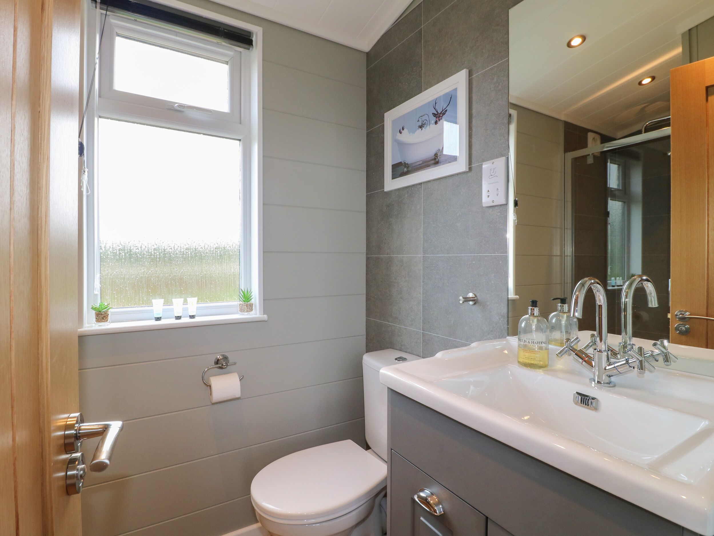 A bathroom with a toilet, sink, and window.