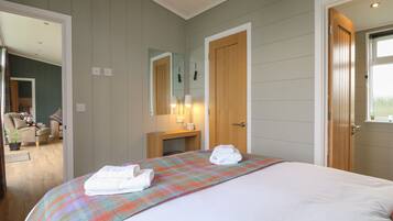 Une chambre à coucher avec un lit, une table de chevet avec une lampe, un miroir et une porte donnant sur une autre pièce.