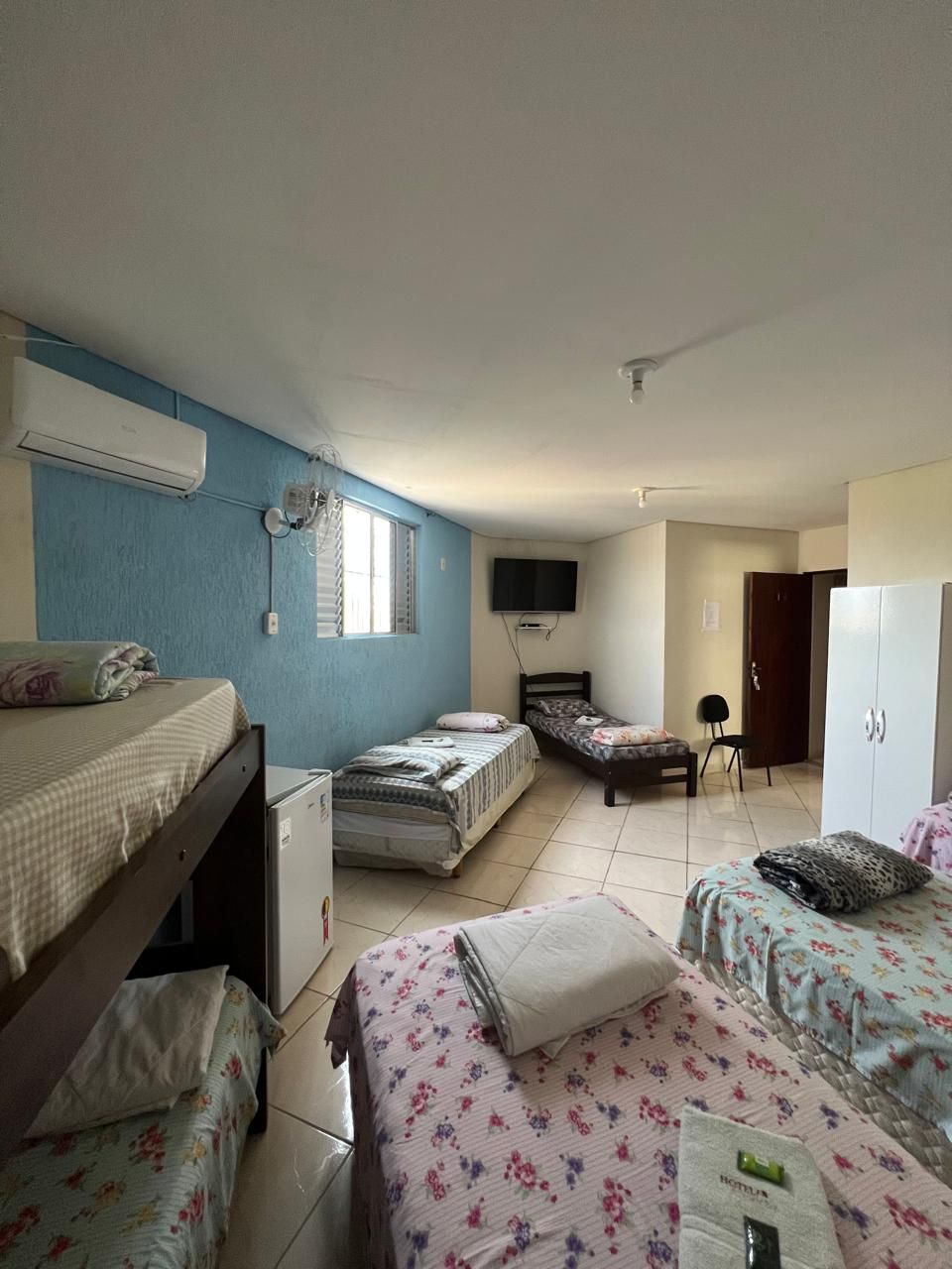 Habitación tipo dormitorio con literas, un escritorio, una silla, un televisor y un armario.