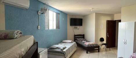 Habitación tipo dormitorio con literas, un escritorio, una silla, un televisor y un armario.