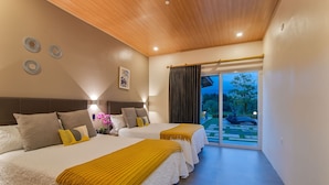 Ein Schlafzimmer mit zwei Betten, einer Holzbalkendecke und Blick auf einen Garten durch eine Schiebetür.