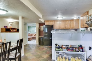 A kitchen with wooden cabinets, a refrigerator, and a countertop with various items. - Lovely Salt Lake City Cottage w/ Outdoor Space! (Salt Lake City)