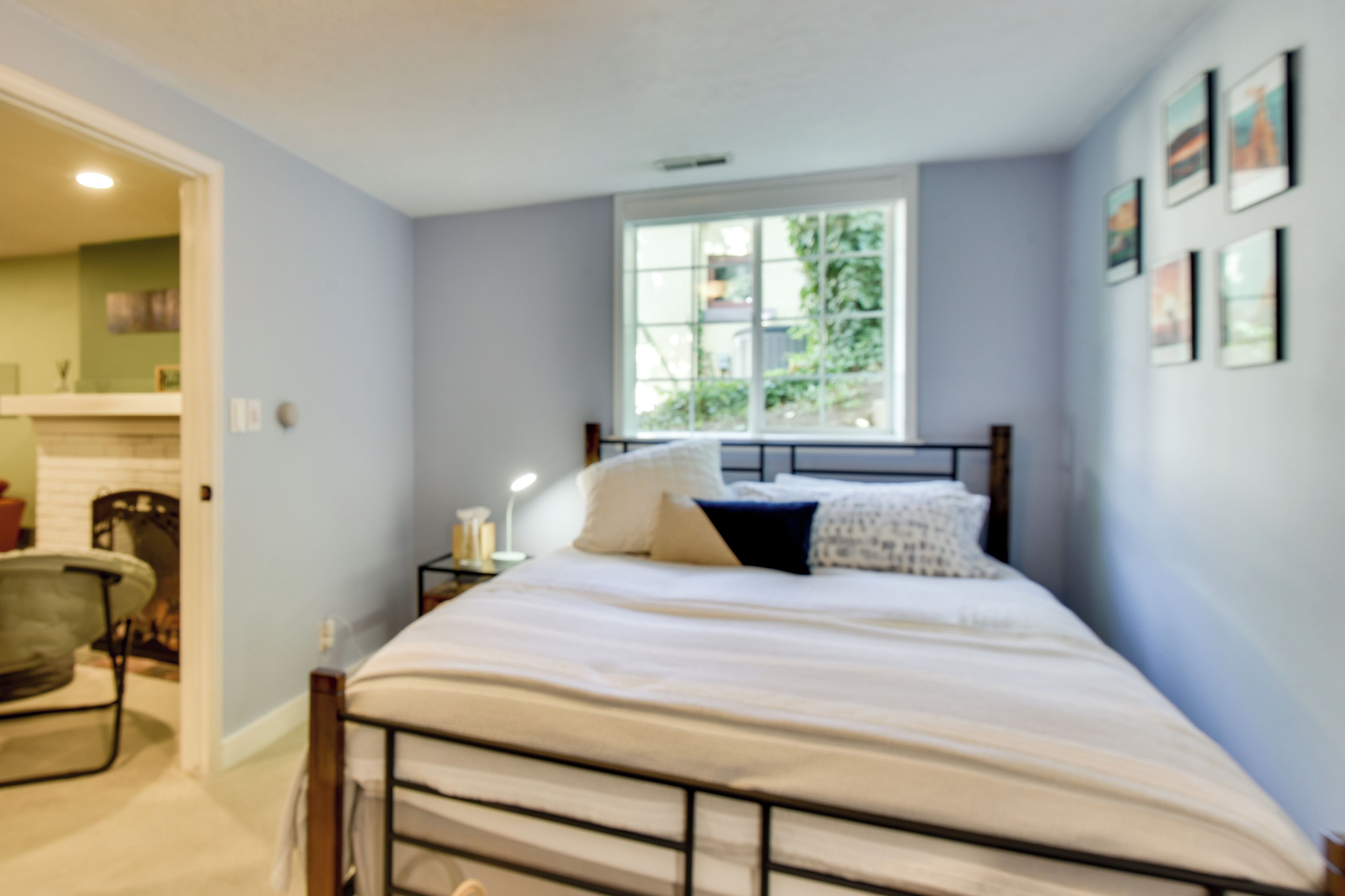 A bedroom with a bed, a window, and a nightstand with a lamp.