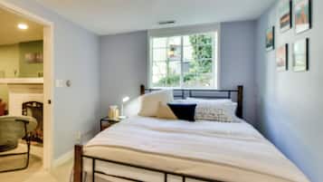 A bedroom with a bed, a window, and a nightstand with a lamp.