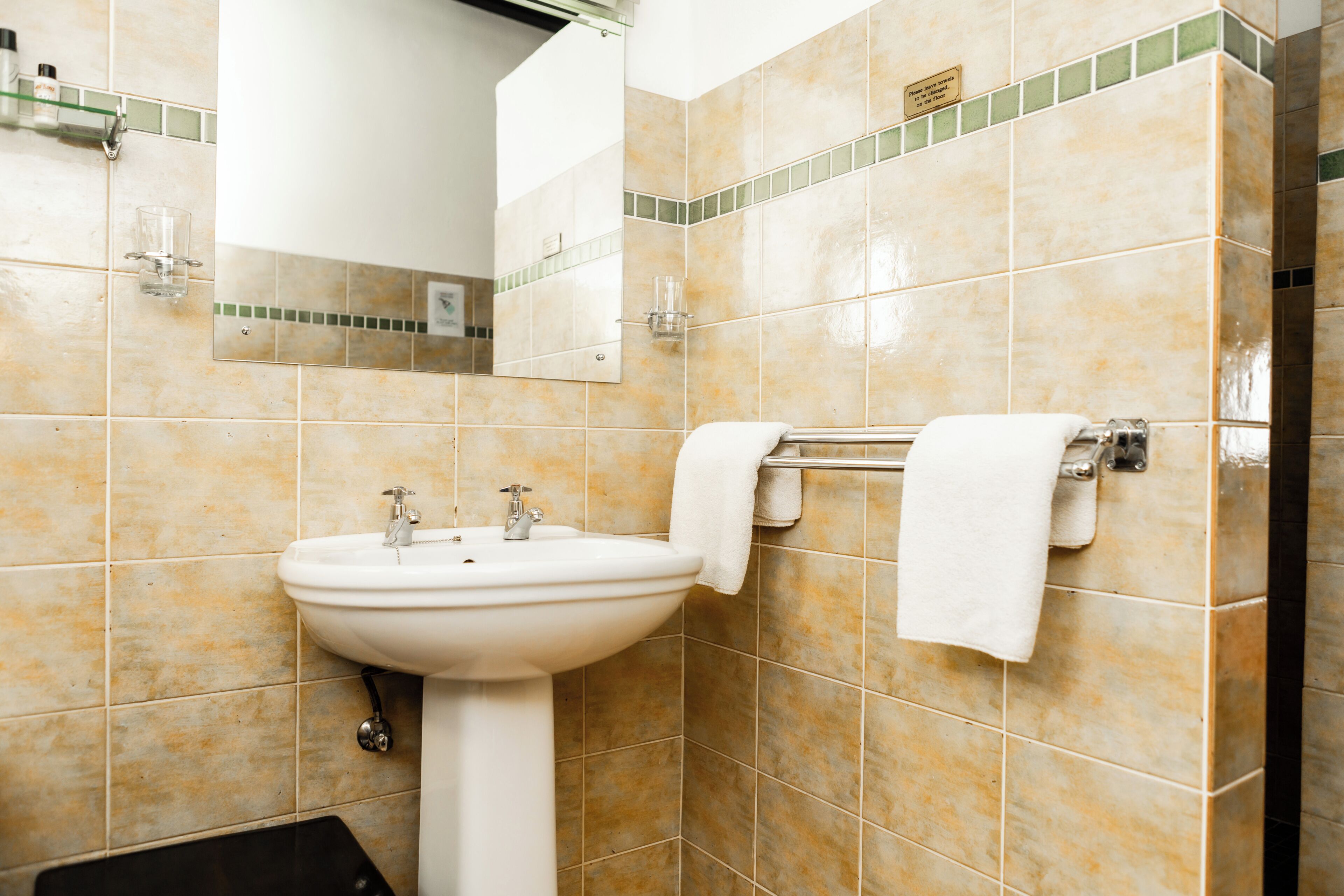 A bathroom with a white sink, mirror, and towel rack.
