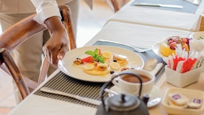 Een eettafel gedekt met eten, een theepot en een kop koffie.