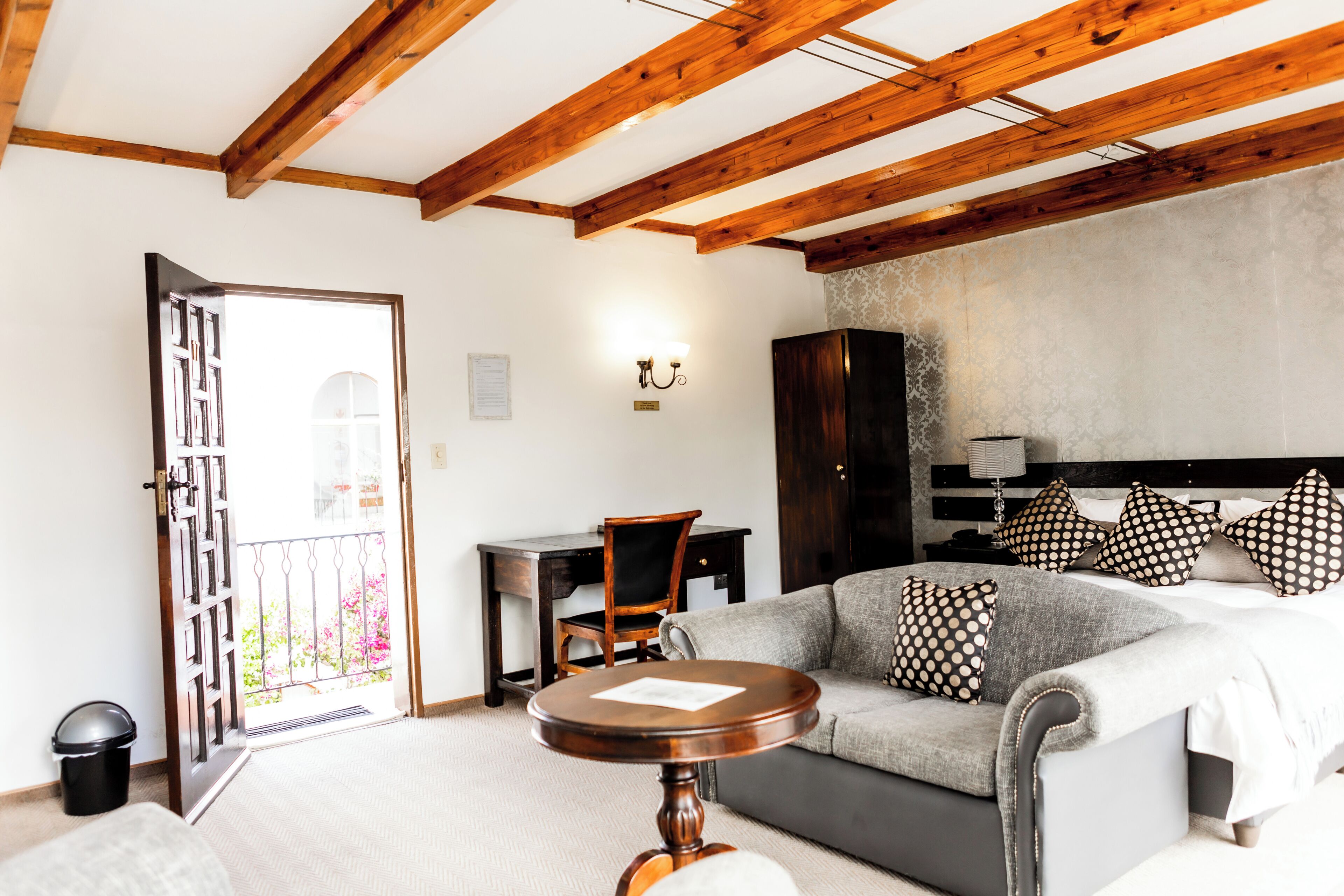 Une pièce comprenant un lit, un canapé, un plafond en bois, un bureau et une chaise.