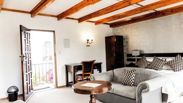 Une pièce comprenant un lit, un canapé, un plafond en bois, un bureau et une chaise.