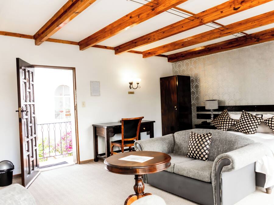 Une pièce comprenant un lit, un canapé, un plafond en bois, un bureau et une chaise.