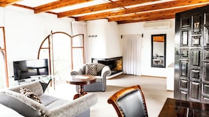 Een woonkamer met een open haard, een televisie en een eethoek met een tafel en stoelen.